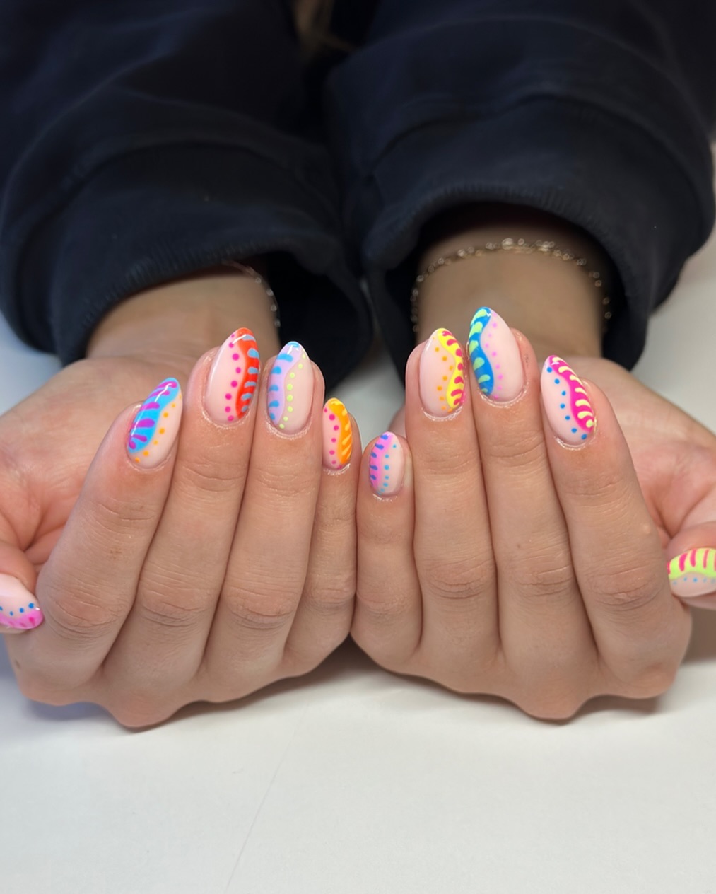 Nude almond nails with rainbow neon dot and stripe nail art