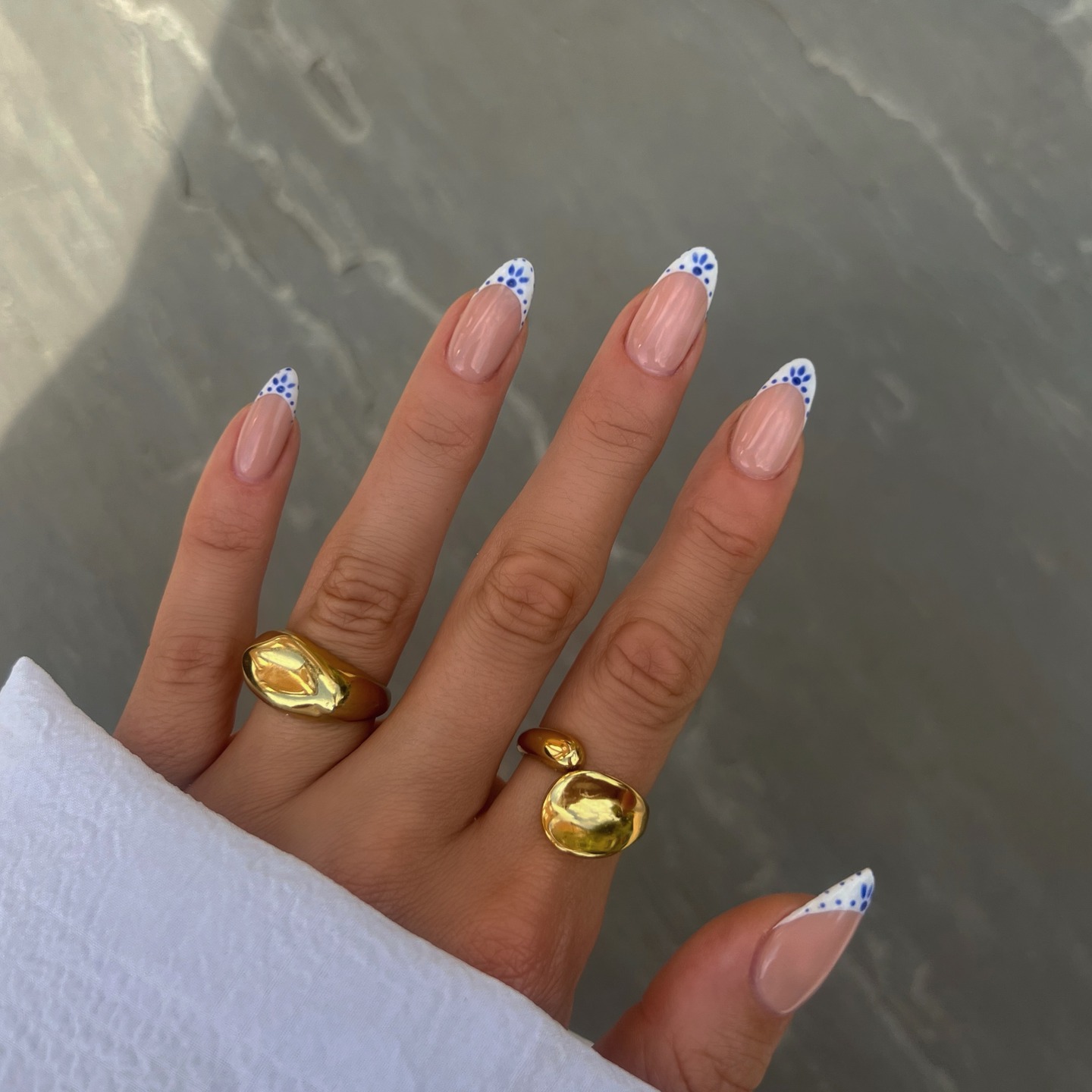 Nude almond nails with white French tips and blue floral dots