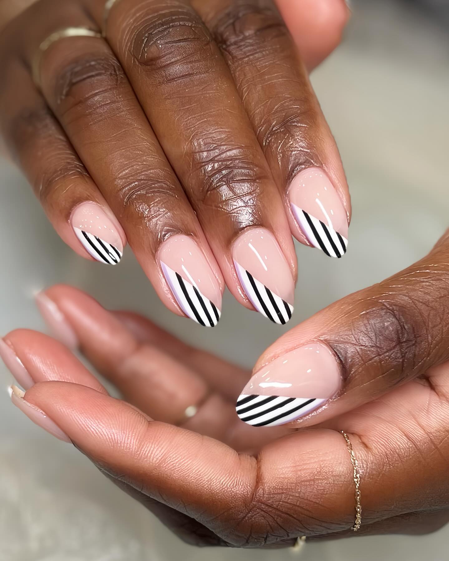 Almond nails with nude base and diagonal black and white stripe tips