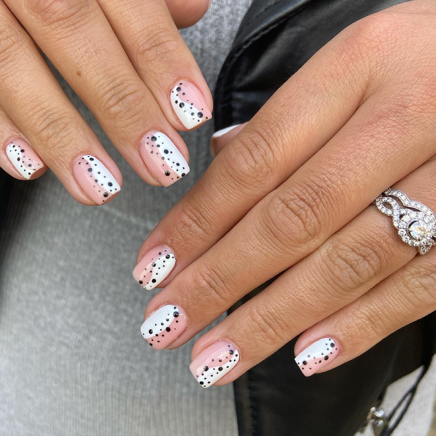 Nude nails with diagonal white French tips and black polka dots