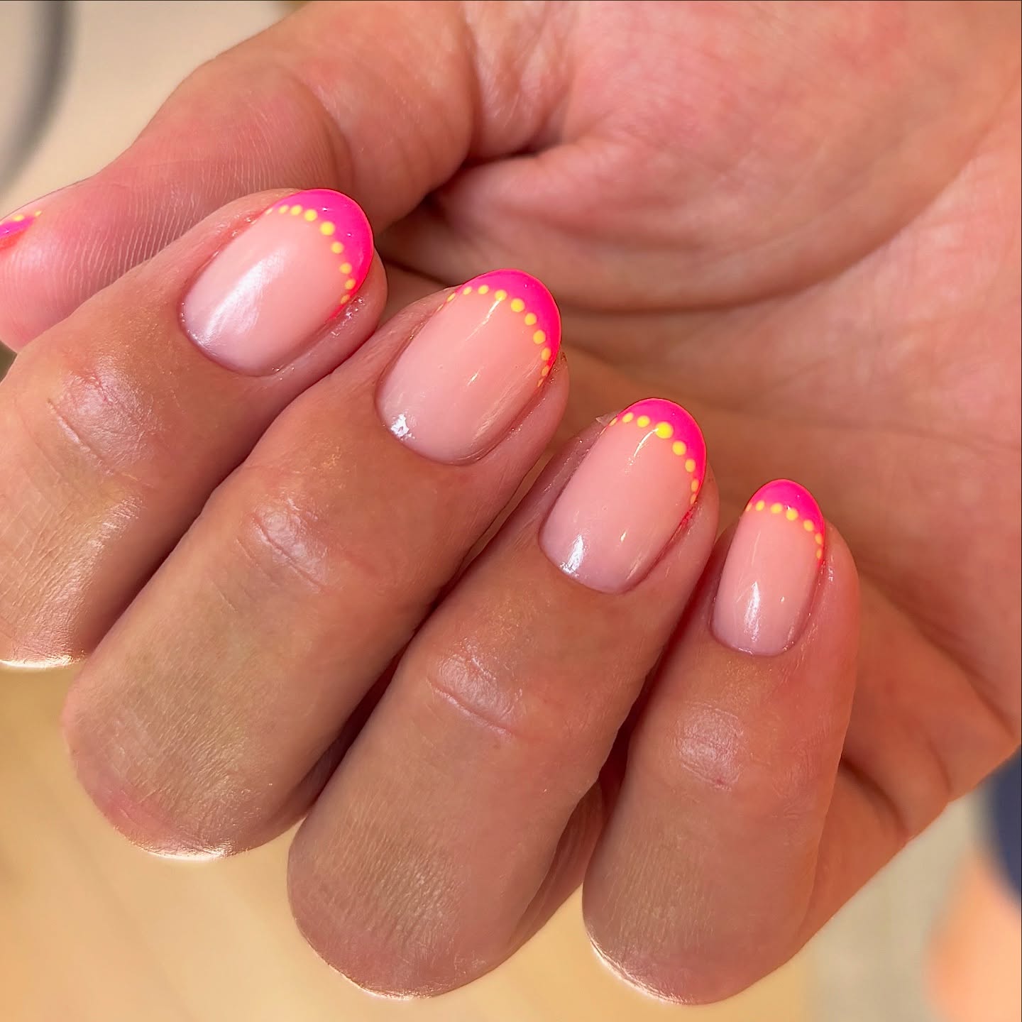 Nude nails with hot pink French tips and neon yellow dot trim