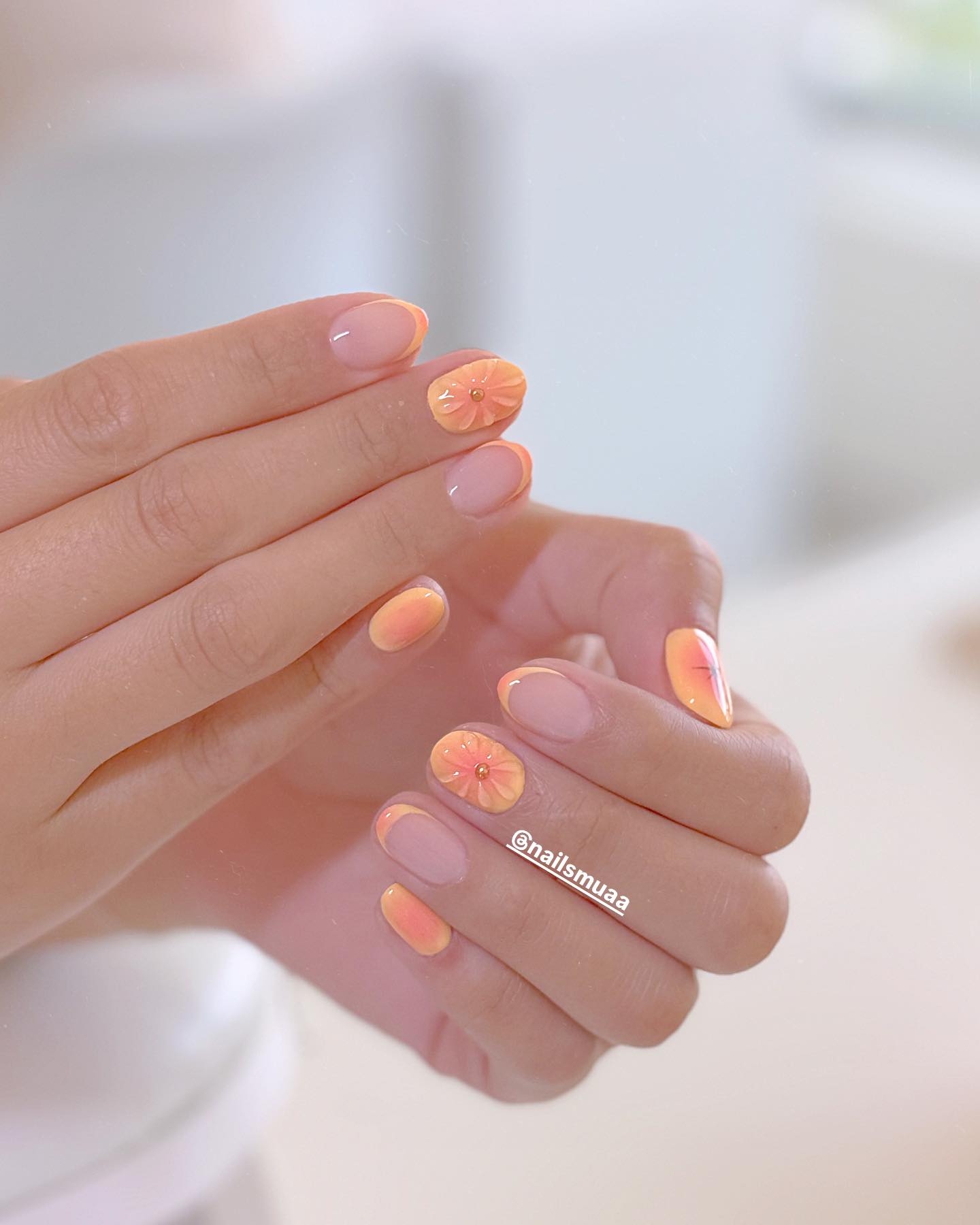 Nude almond nails with peach French tips and 3D flower accent