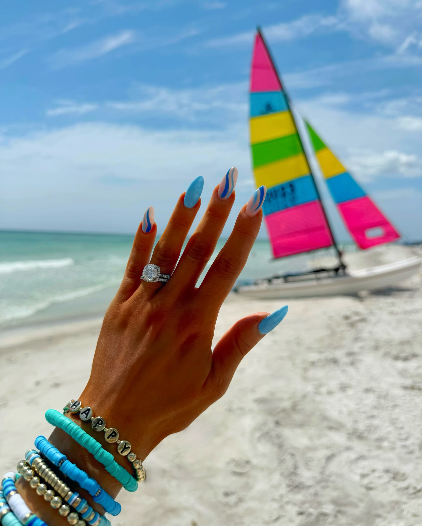 Blue almond nails with white wave swirls at the beach