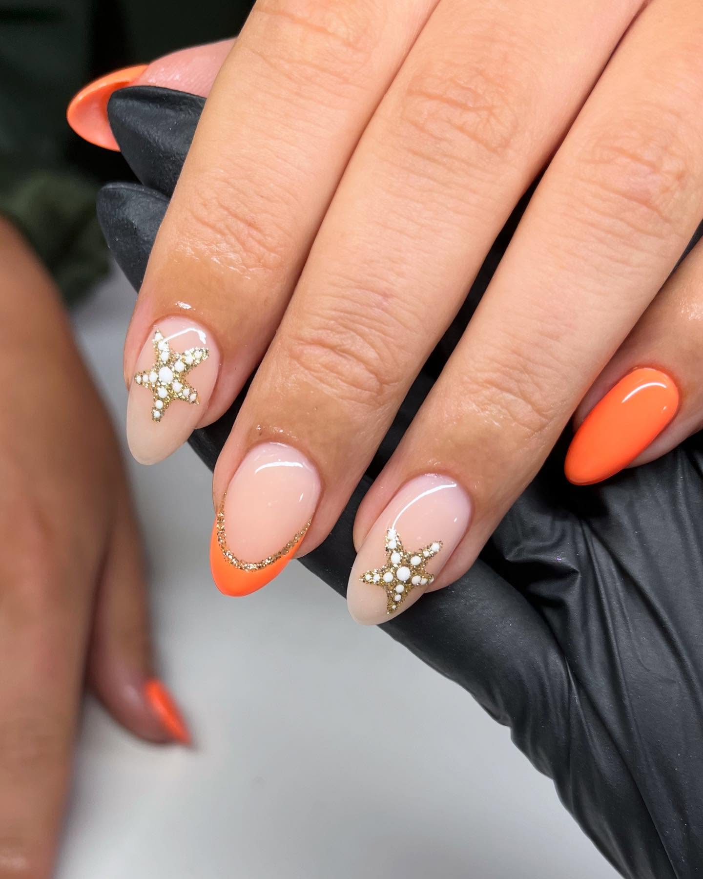 Orange French tips with gold glitter starfish on nude almond nails