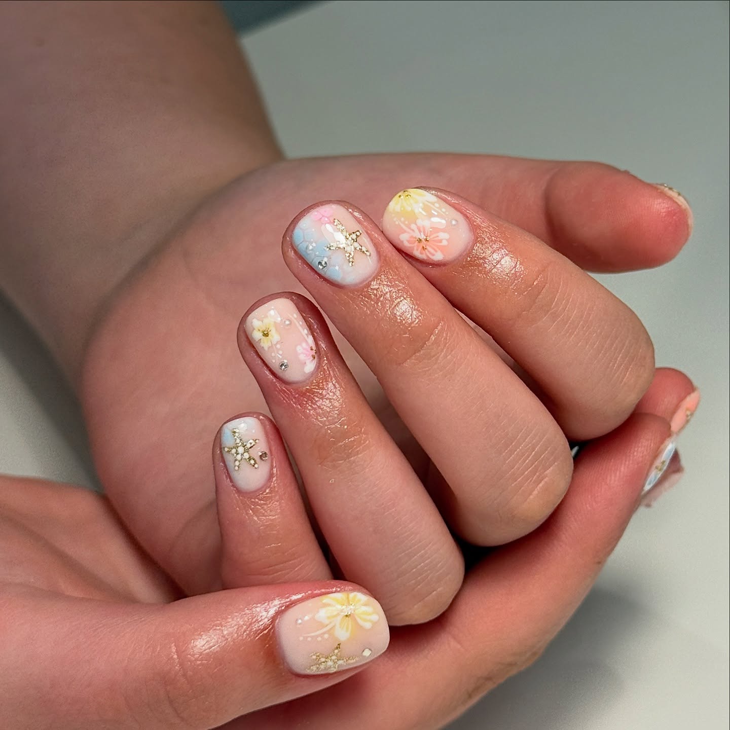 Pastel peach aura nails with painted florals and glitter starfish