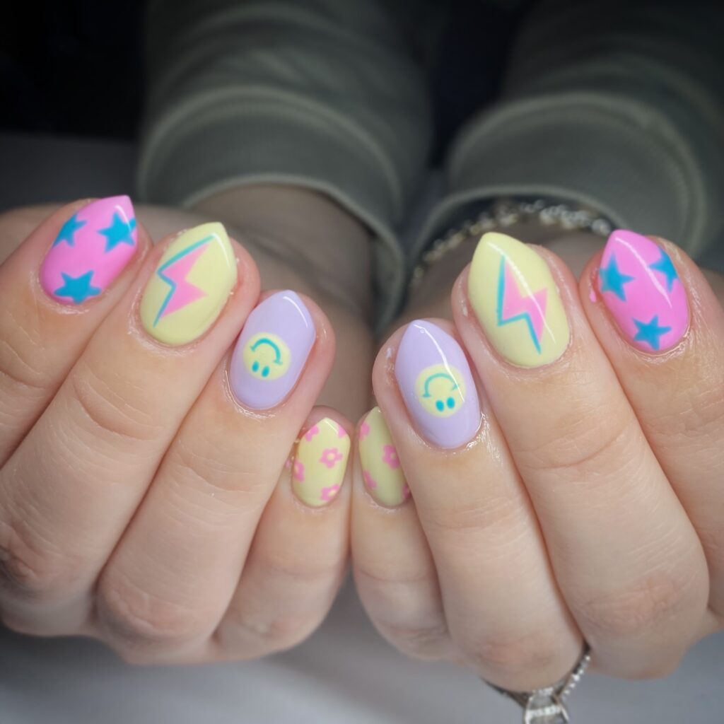 nails with teal stars, lightning bolts, smiley face, and floral art