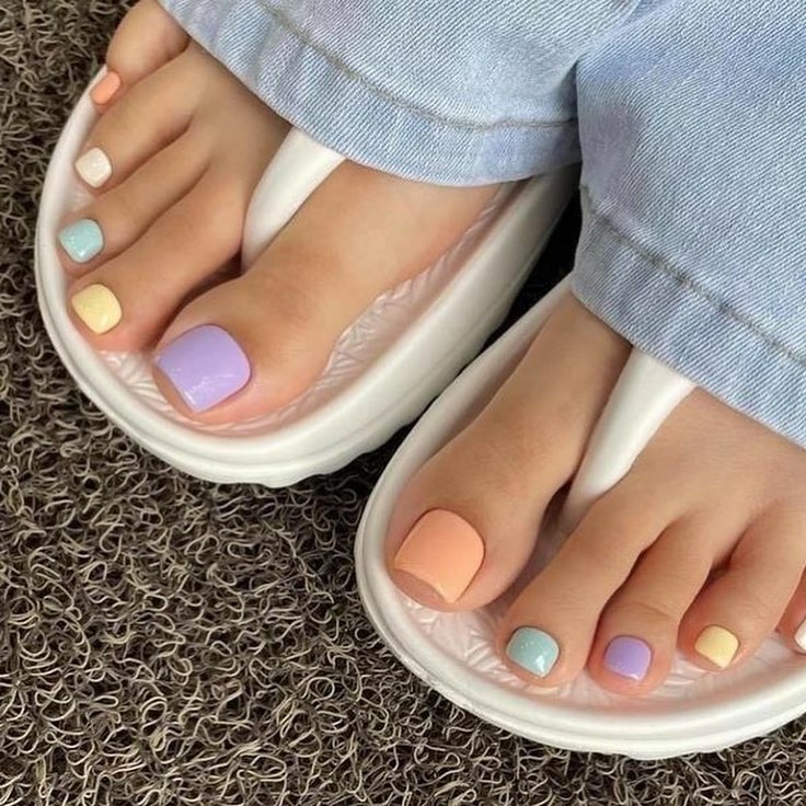 Pastel rainbow toe nails with each toe a different color including peach, lavender, yellow and mint