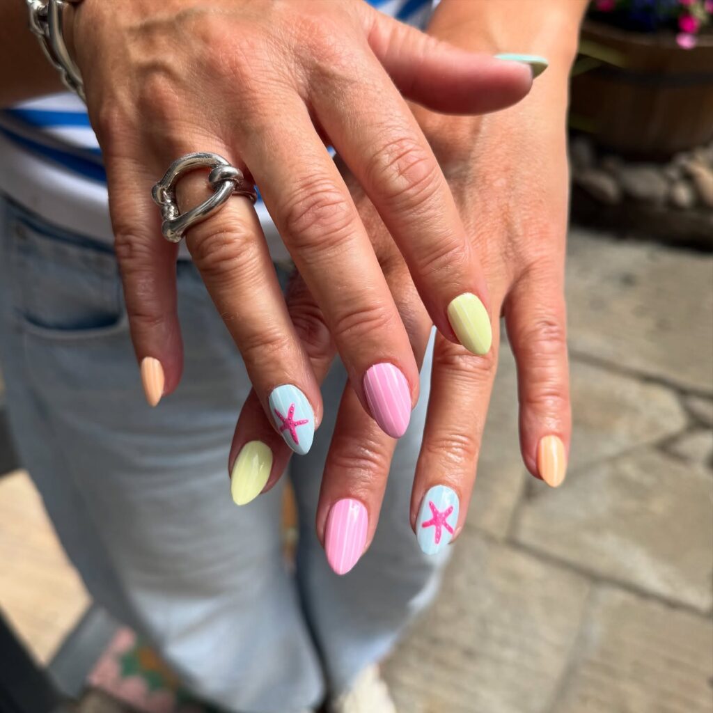 nails in peach, yellow, pink, and blue with a starfish accent nail