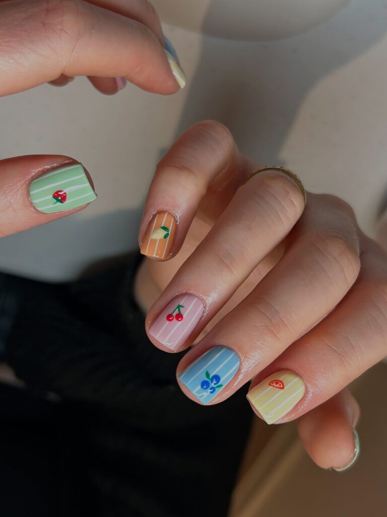 short pastel pinstripe nails with tiny painted fruit motifs