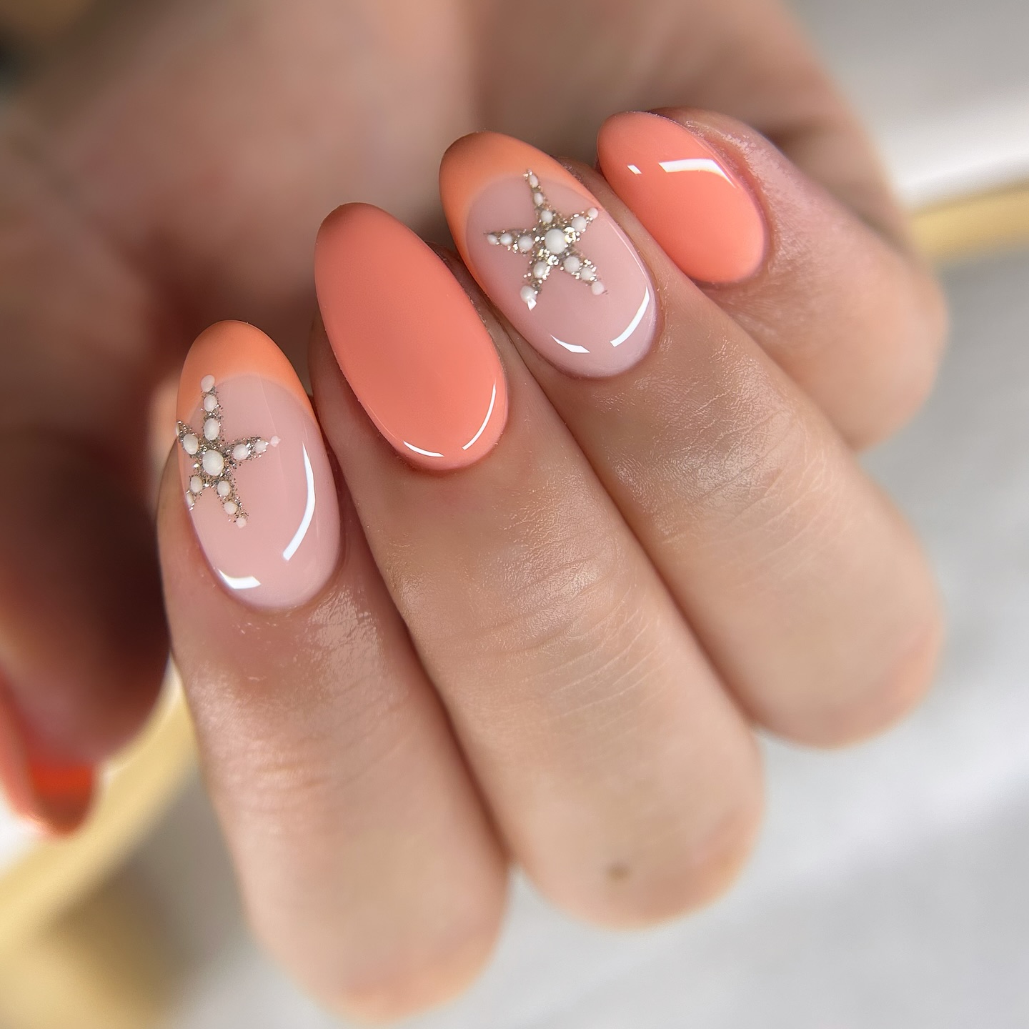 Peach and nude almond nails with pearl rhinestone starfish