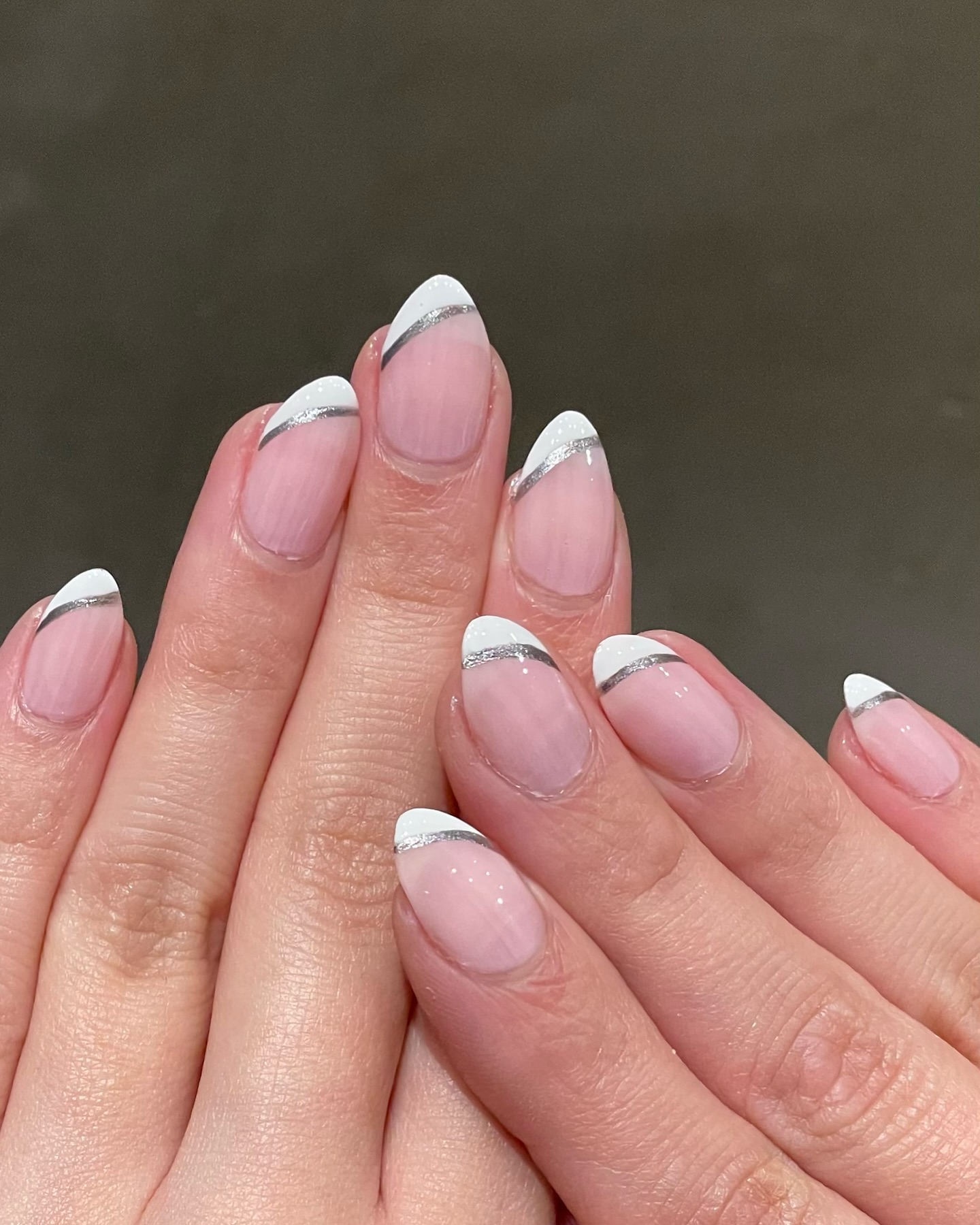 Almond nails with sheer pink base white French tips and silver glitter foil line