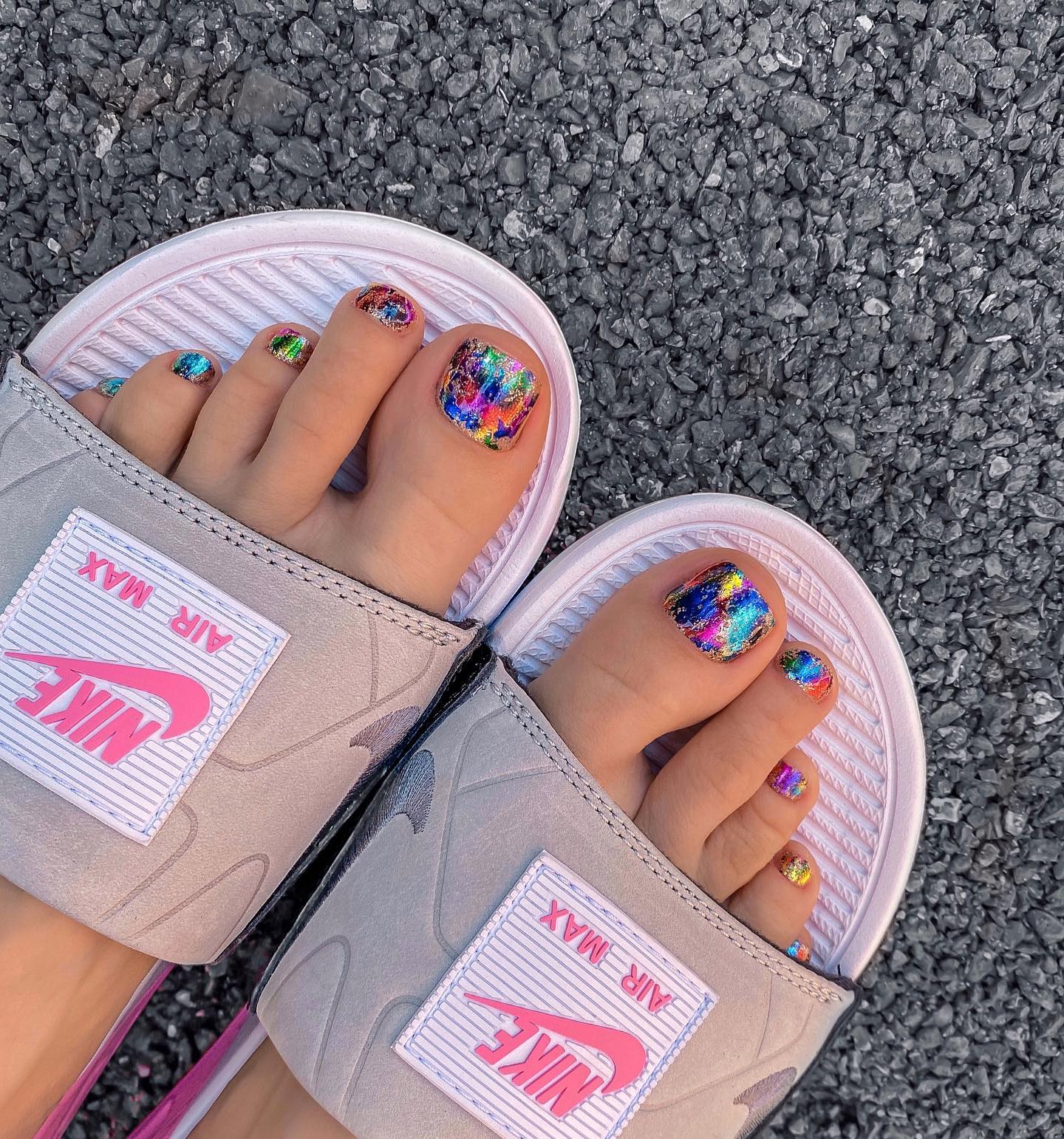Vibrant rainbow holographic foil toe nails worn in Nike Air Max slides