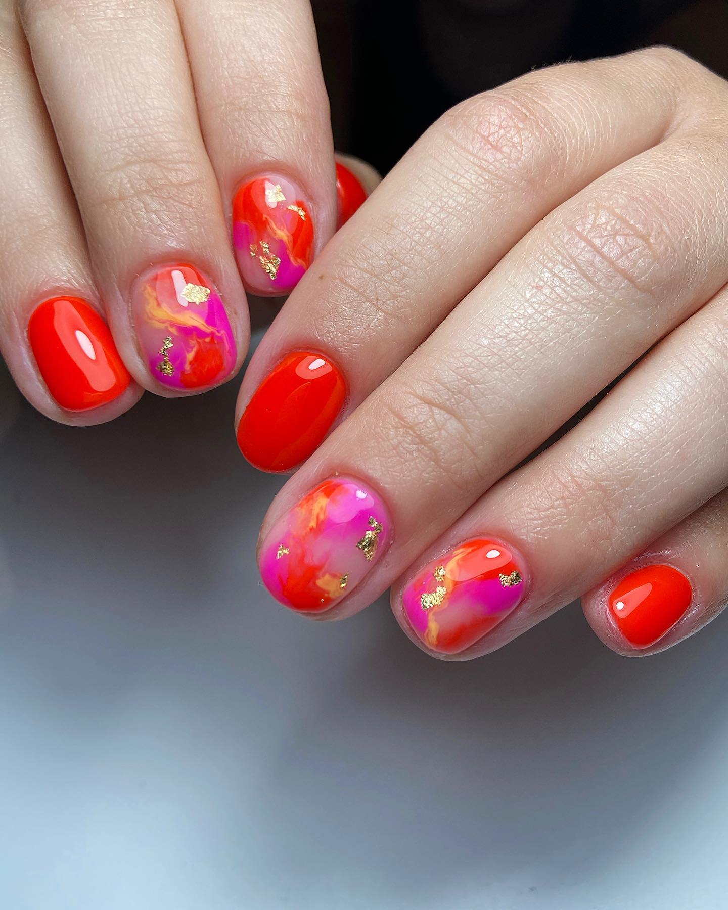 Nails with red and pink marble swirl and gold foil flakes