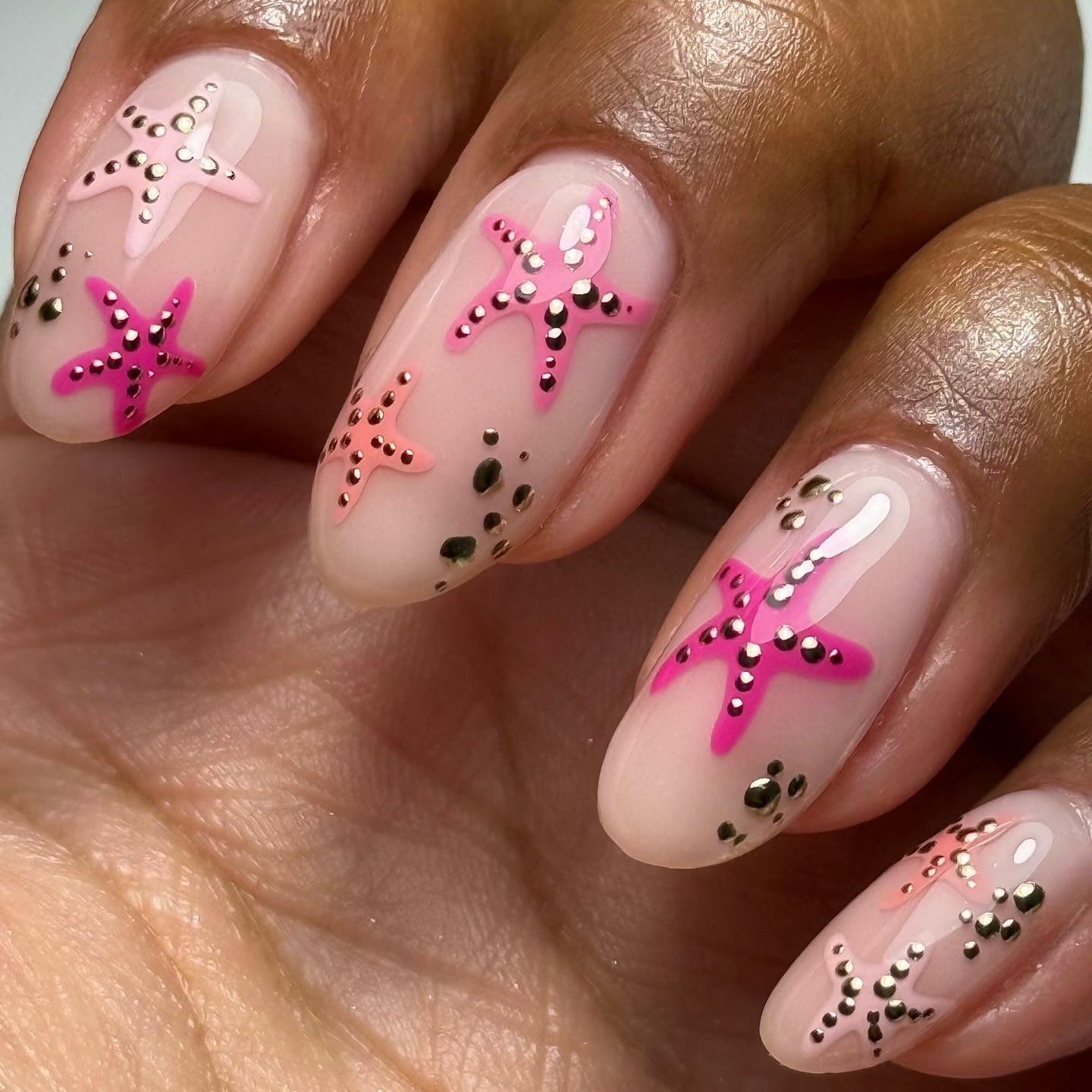 Pink and gold rhinestone starfish on sheer nude almond nails