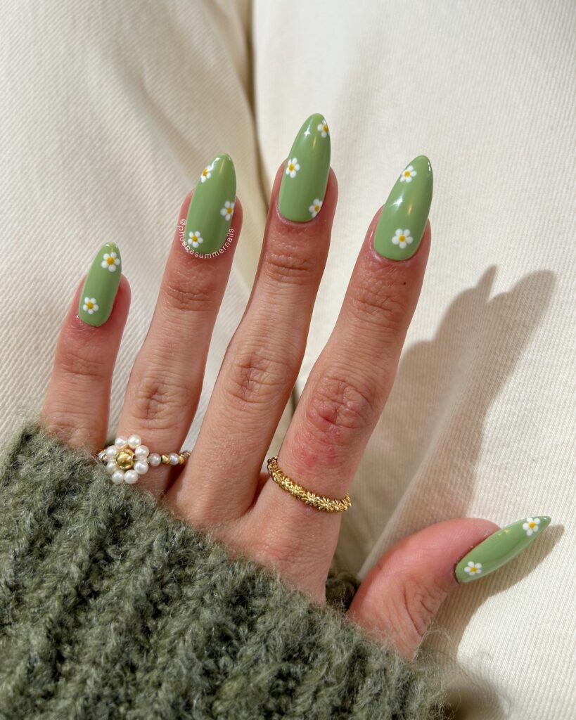 Sage green long almond nails scattered with white and yellow daisy nail art
