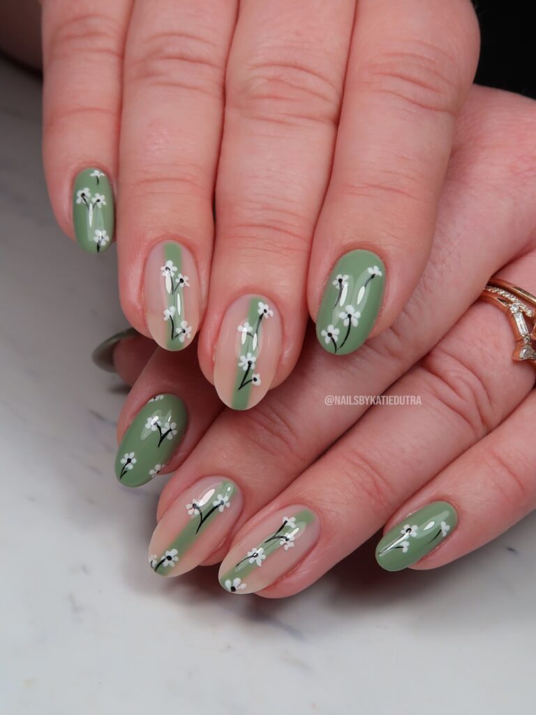 Sage green half moon oval nails with delicate wildflower sprig nail art
