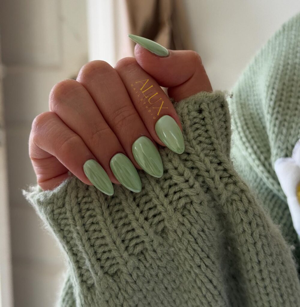 Long almond nails painted in glossy warm sage green solid color
