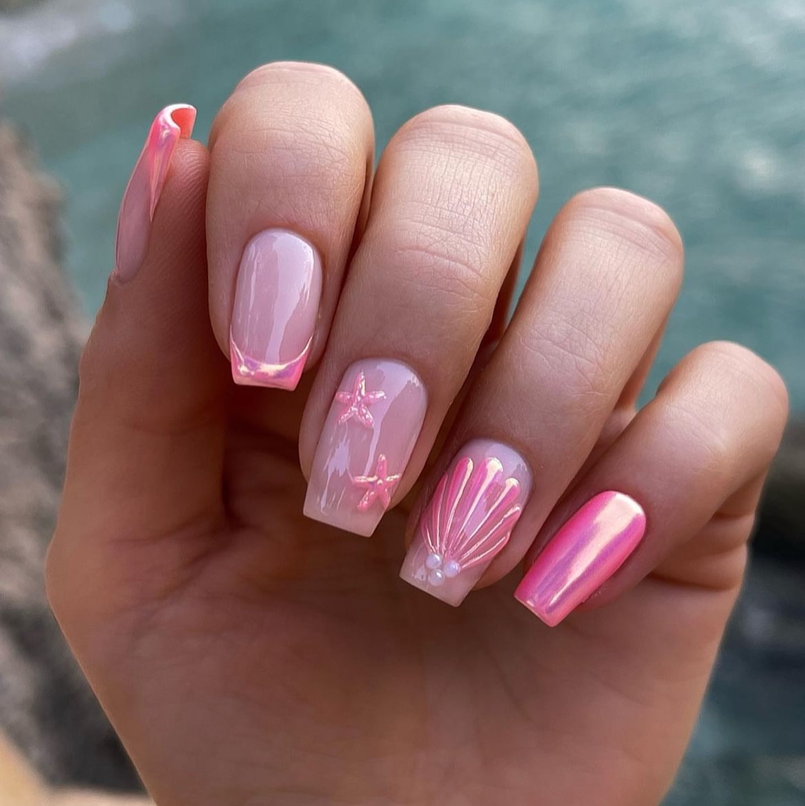 Square nails with iridescent pink chrome, sheer pink starfish and a 3D seashell accent