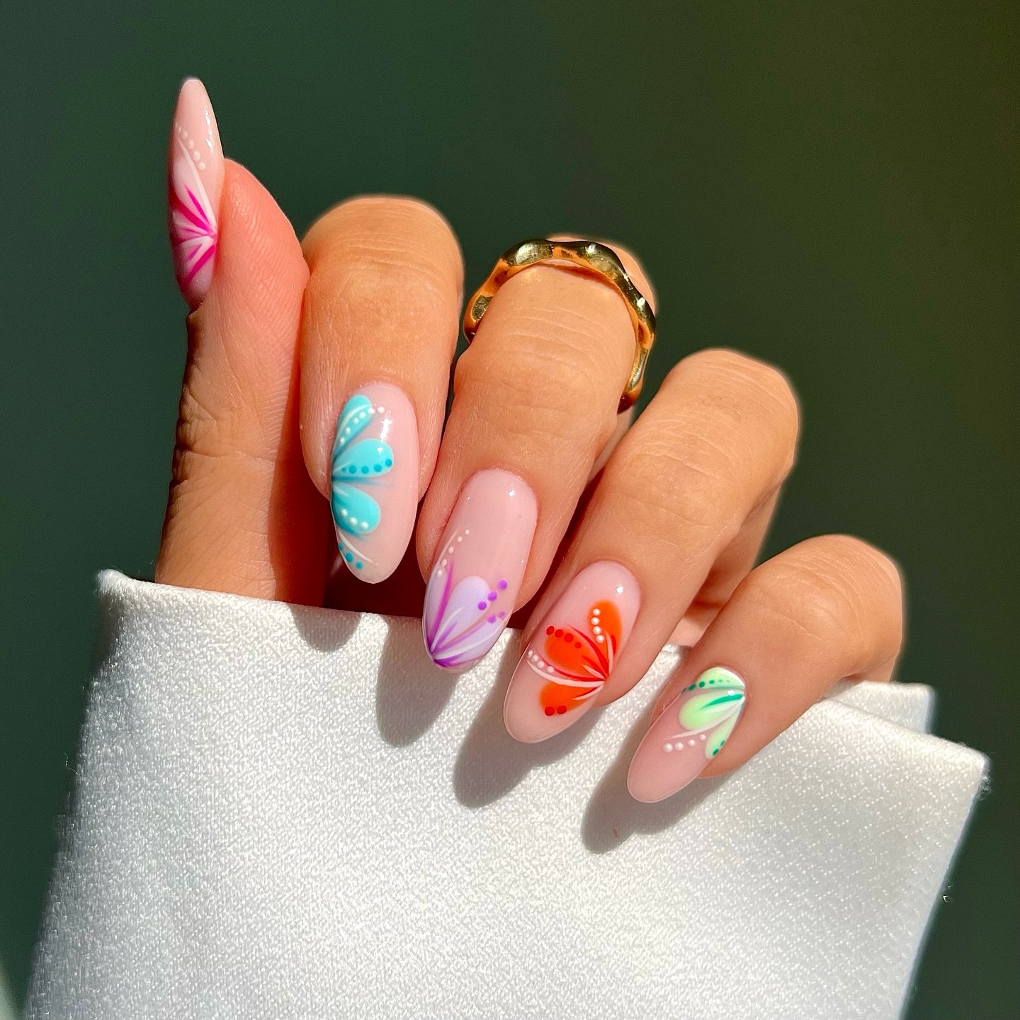 Nude almond nails with individual tropical flowers in bright colours