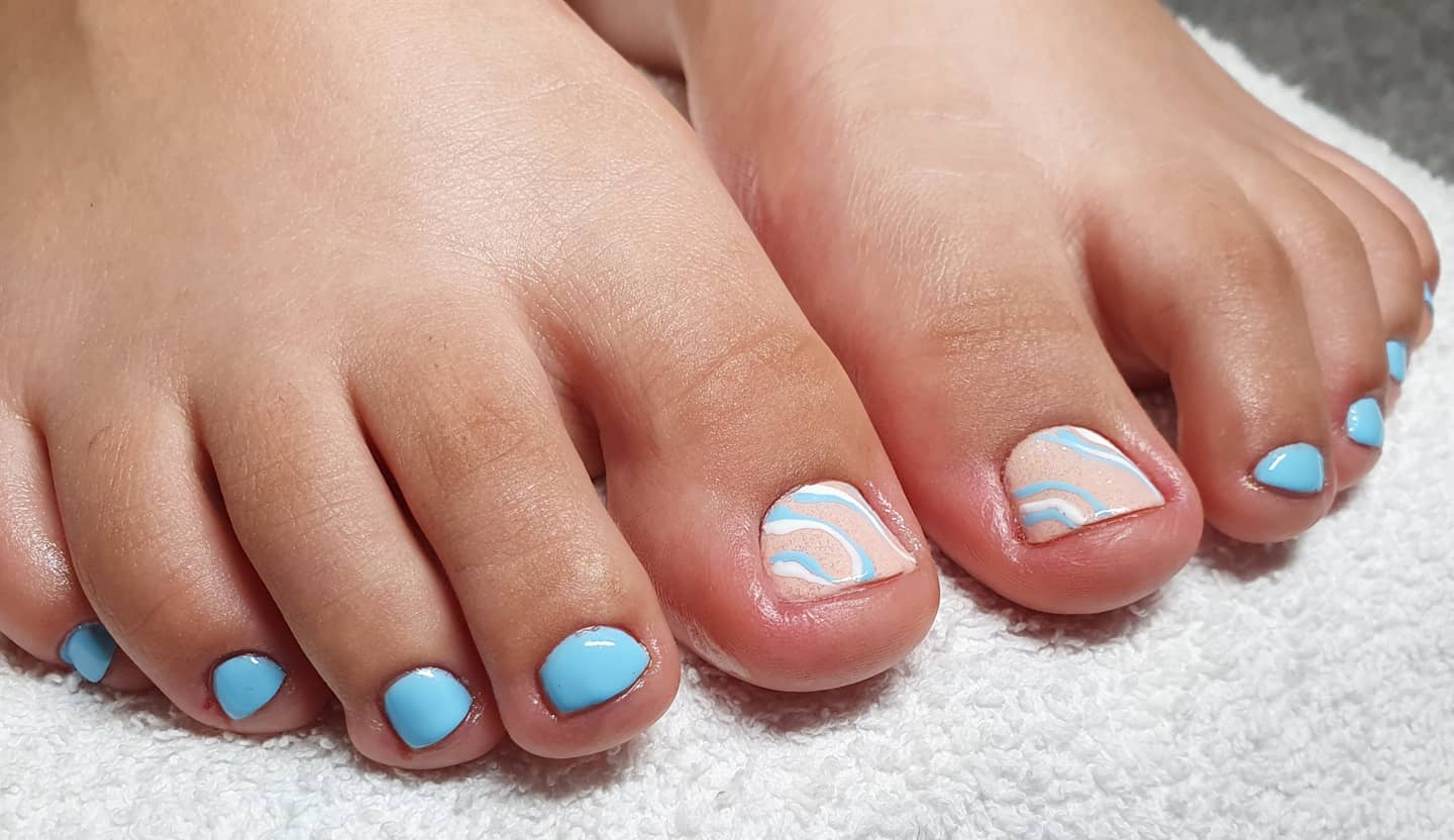 Sky blue toe nails with marble swirl art on big toe in white and blue on white towel