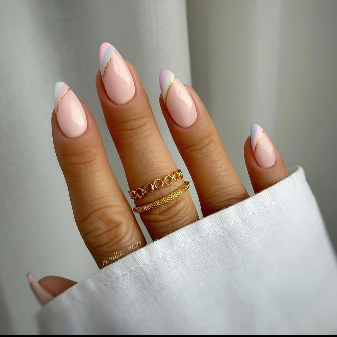 Soft pink almond nails with pastel diagonal tips and gold line