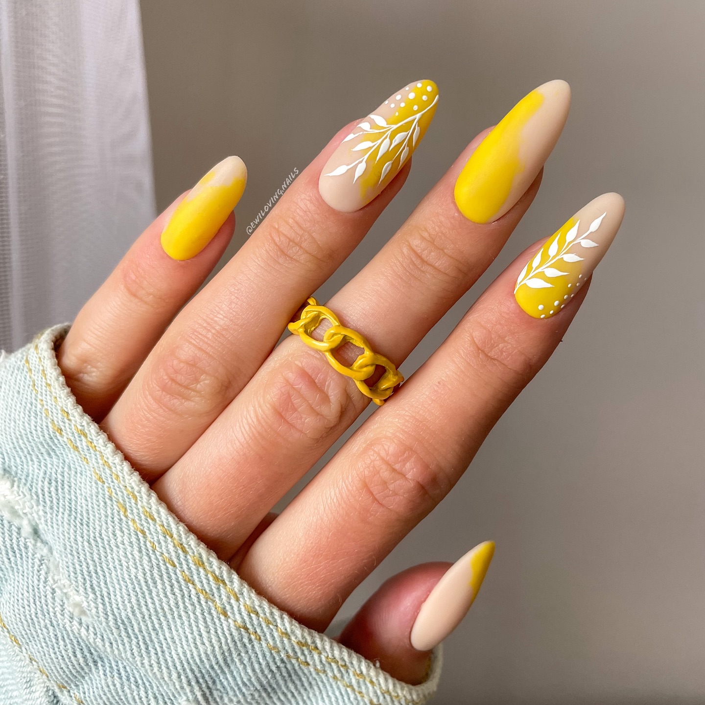 Yellow and beige almond nails with white leaf art