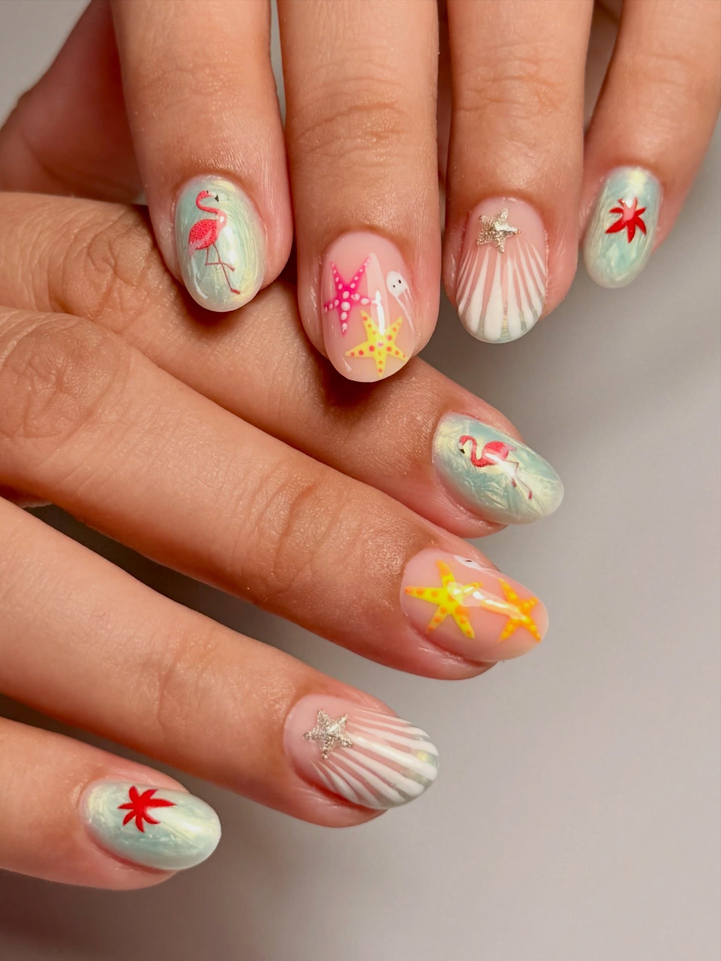 Iridescent mint nails with flamingos, starfish, seashell rays and floral accents