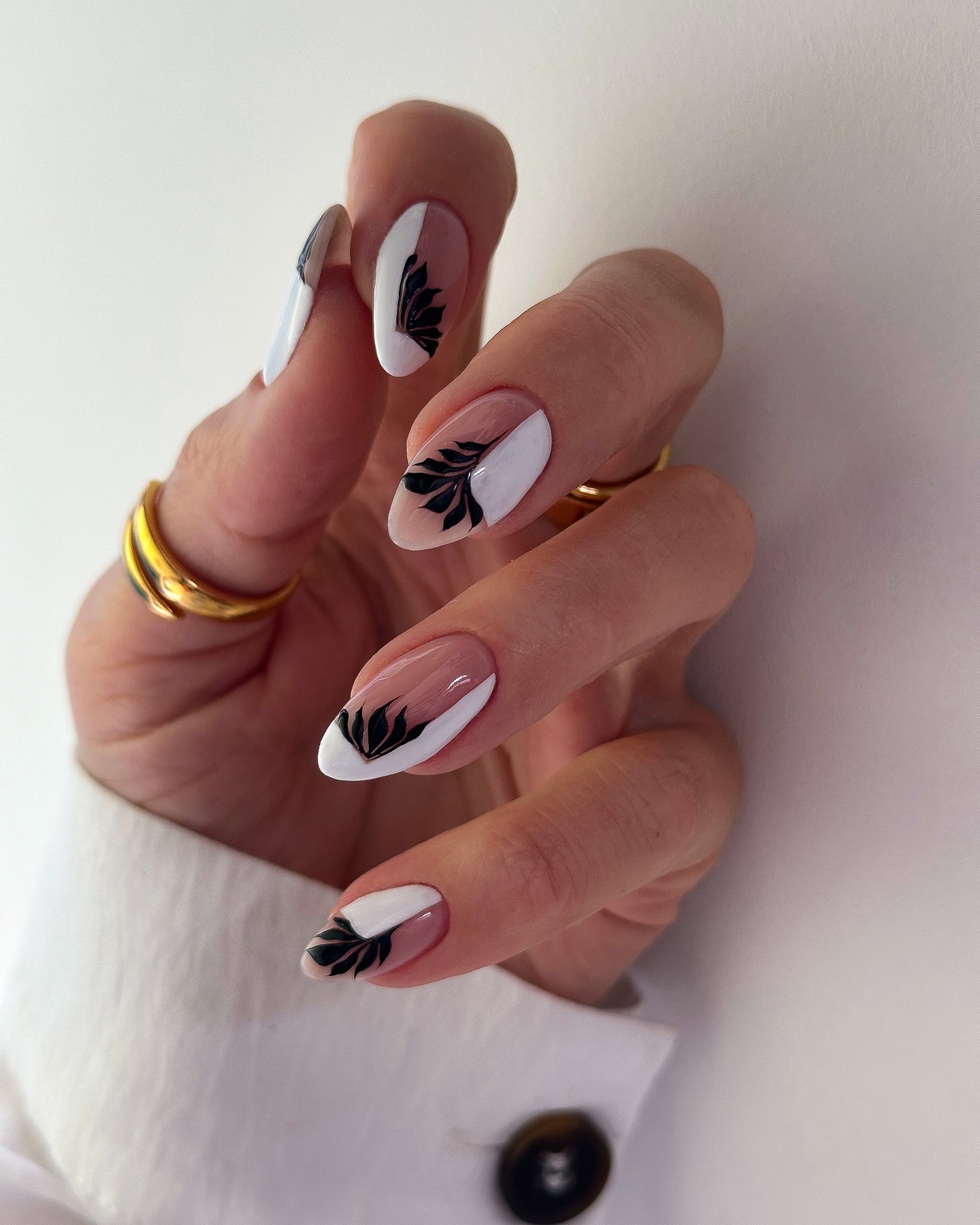 White almond nails with black botanical leaf designs