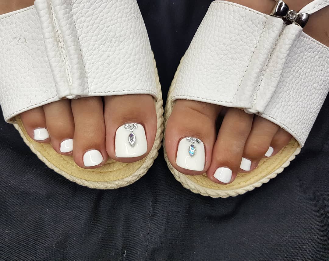 White toe nails with dangling crystal charm on big toe worn in white leather espadrilles