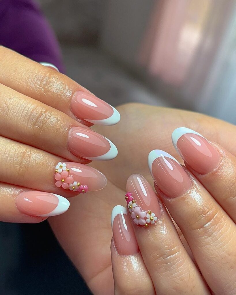 Short oval nails with white tips adorned with clustered 3D pink and white bead flowers and gold ball accents