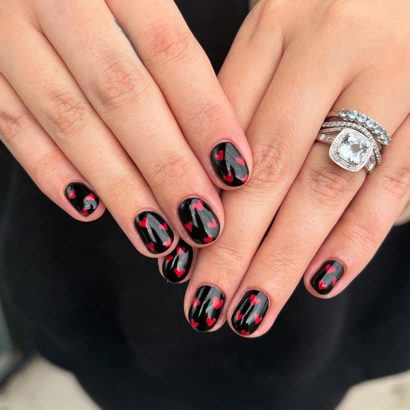 Short round black nails with scattered red heart splatter and drip details