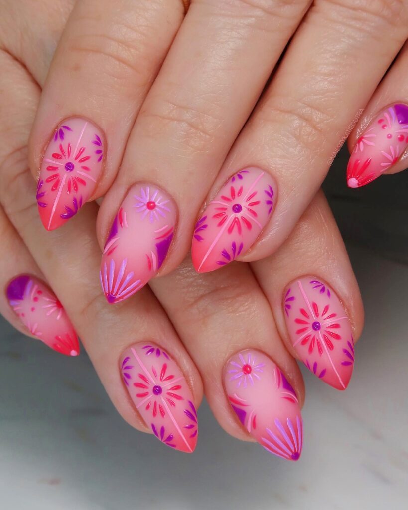 Long almond nails with a coral to sheer pink ombre base and hand-painted purple and pink daisy nail art