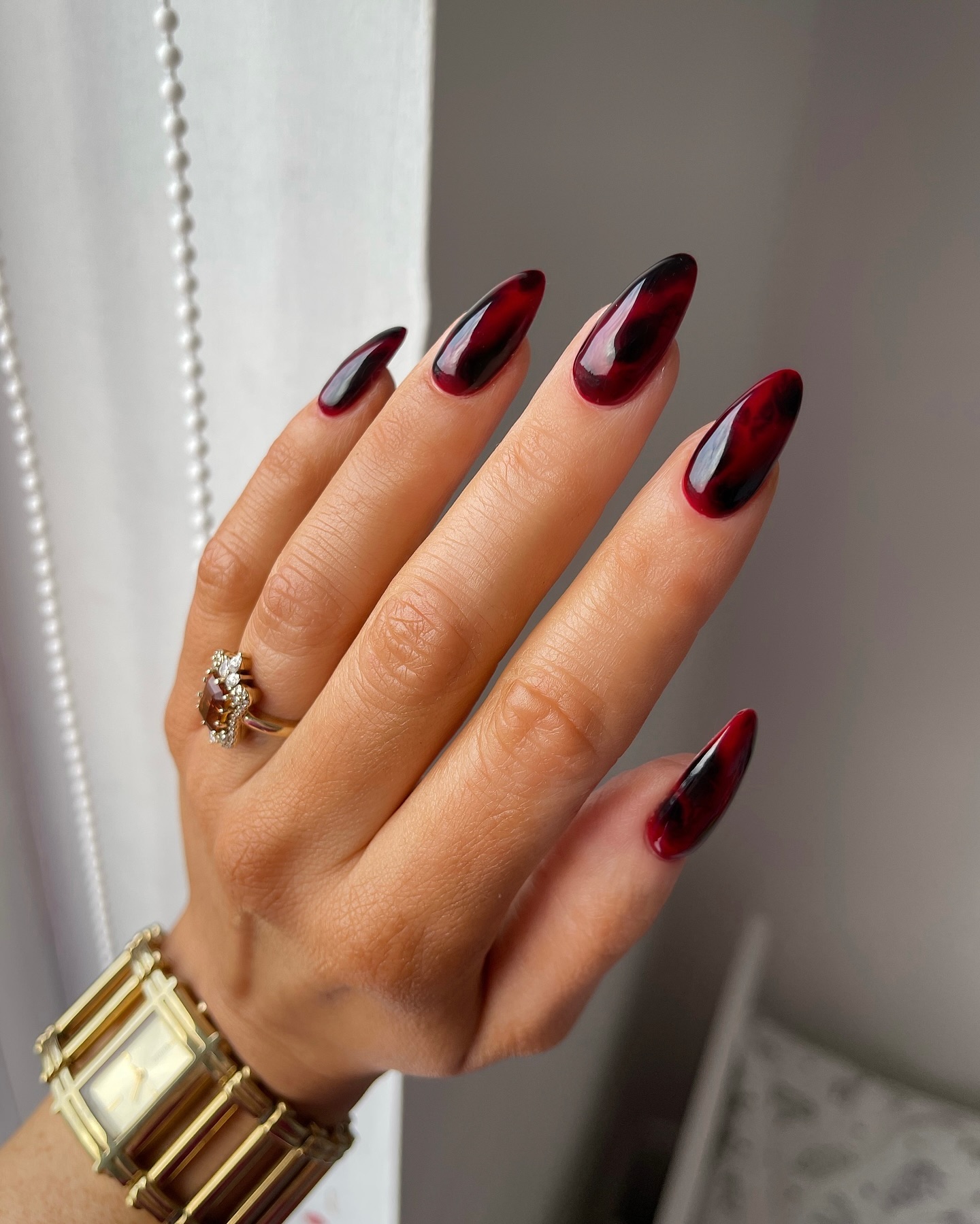 Long almond nails in deep burgundy red with dramatic black smoky tips