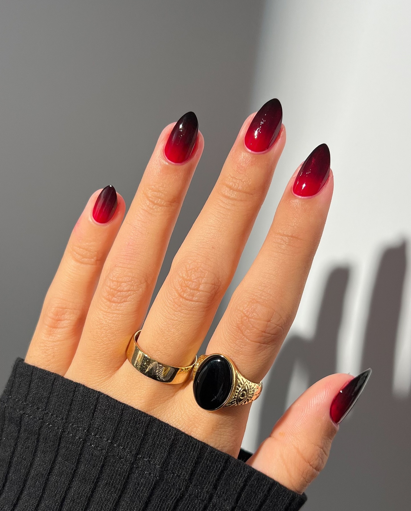Long almond nails in deep red fading to near-black at the tips with a glossy finish