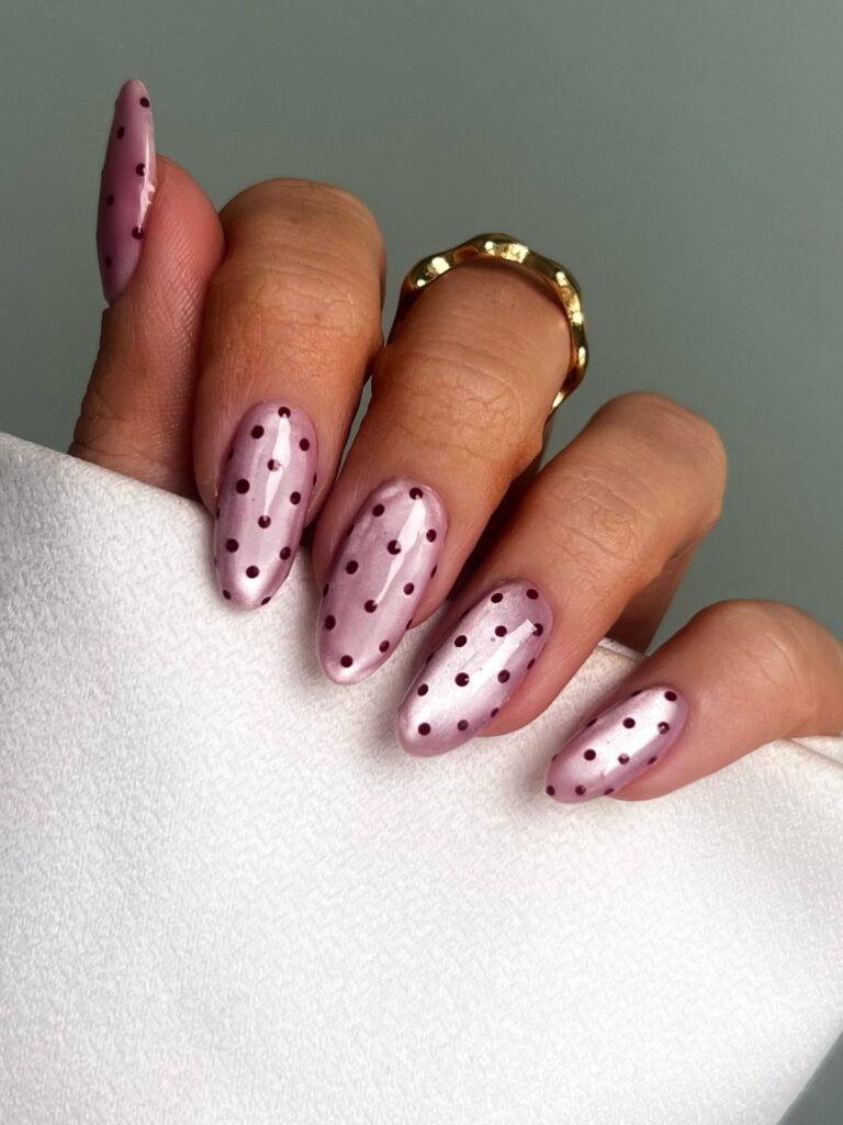 Long almond nails in dusty mauve pink with tiny deep burgundy polka dots — understated and quietly elegant