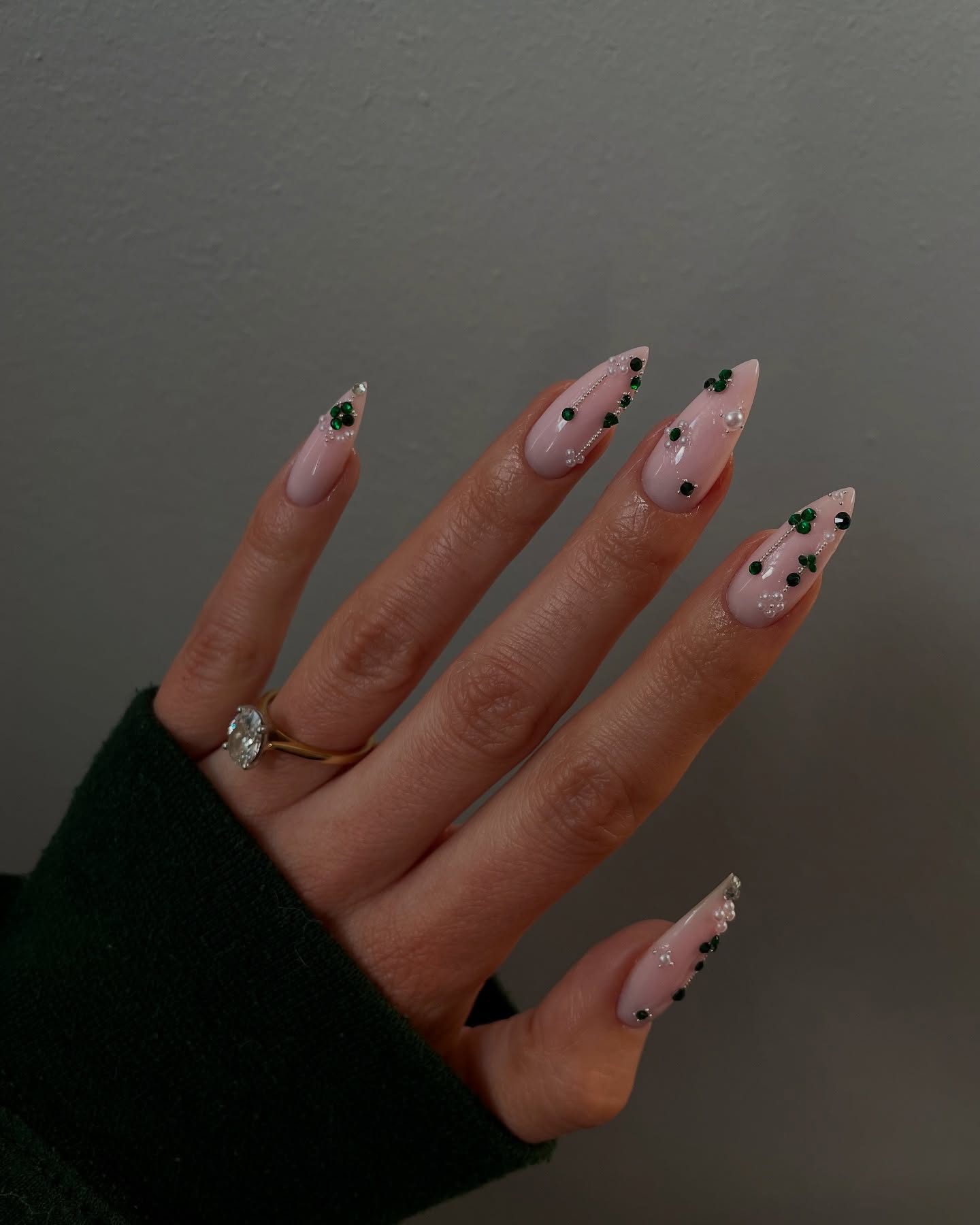 Long almond nails with emerald green and black rhinestones and silver detail on a nude base