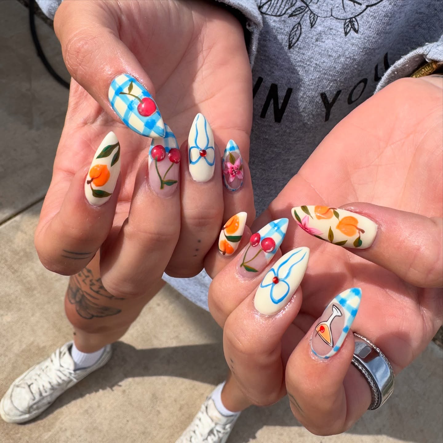 Blue gingham stiletto nails with hand-painted cherries, peach fruit, and bows