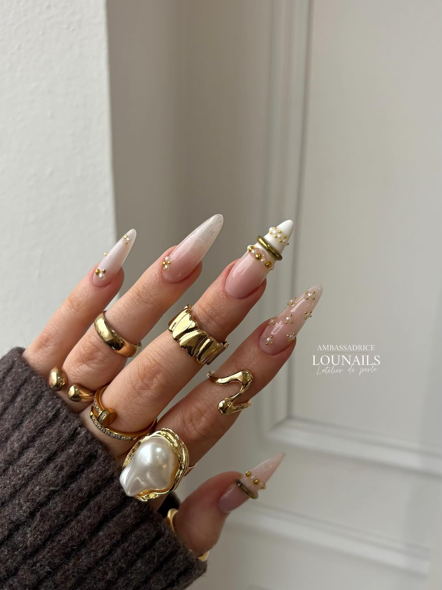 Long stiletto nails with sheer pink ombre and delicate gold rings with tiny rhinestone accents