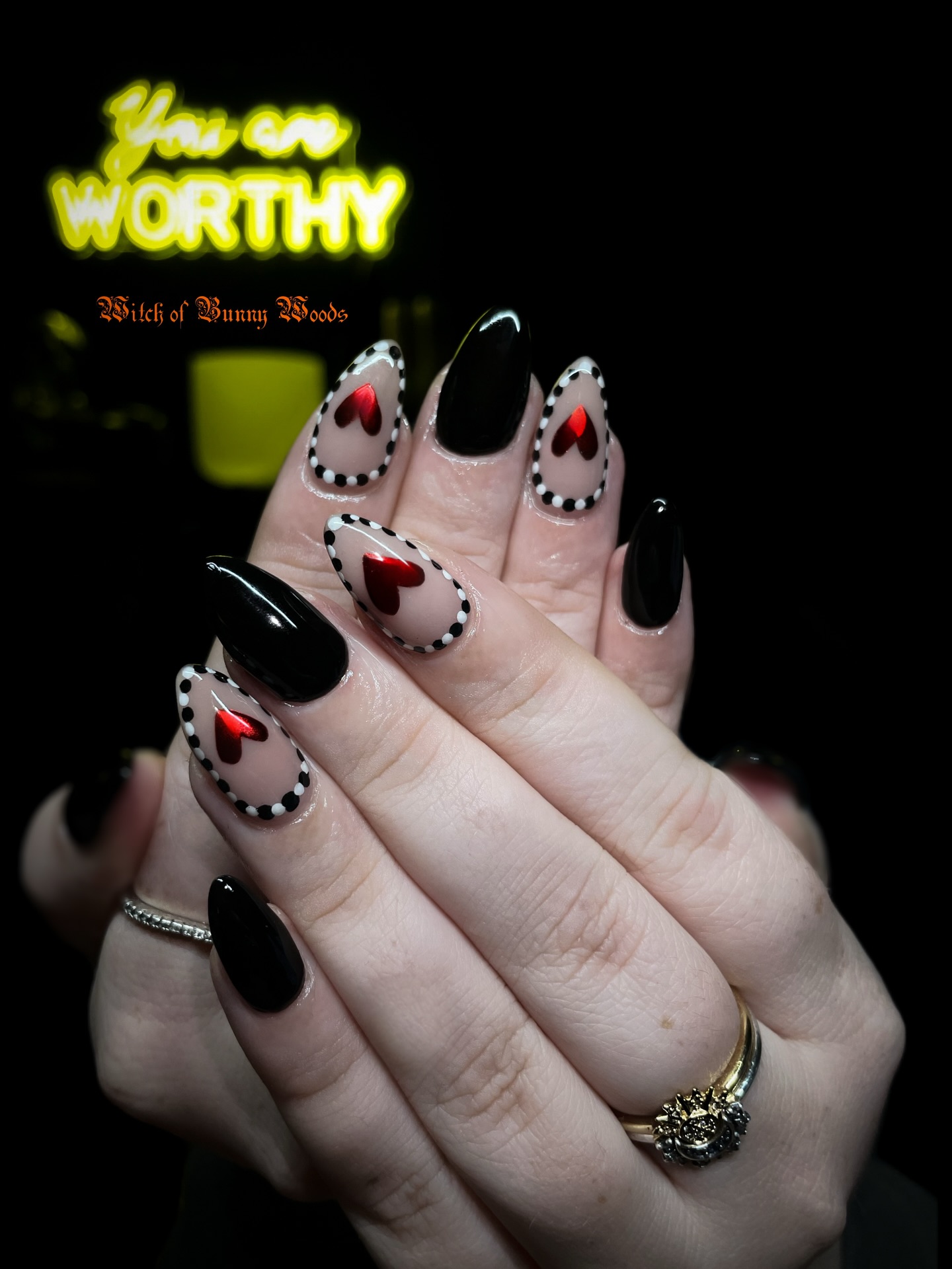 Long black stiletto nails with sheer cutout window effect, red hearts, and dotted black borders