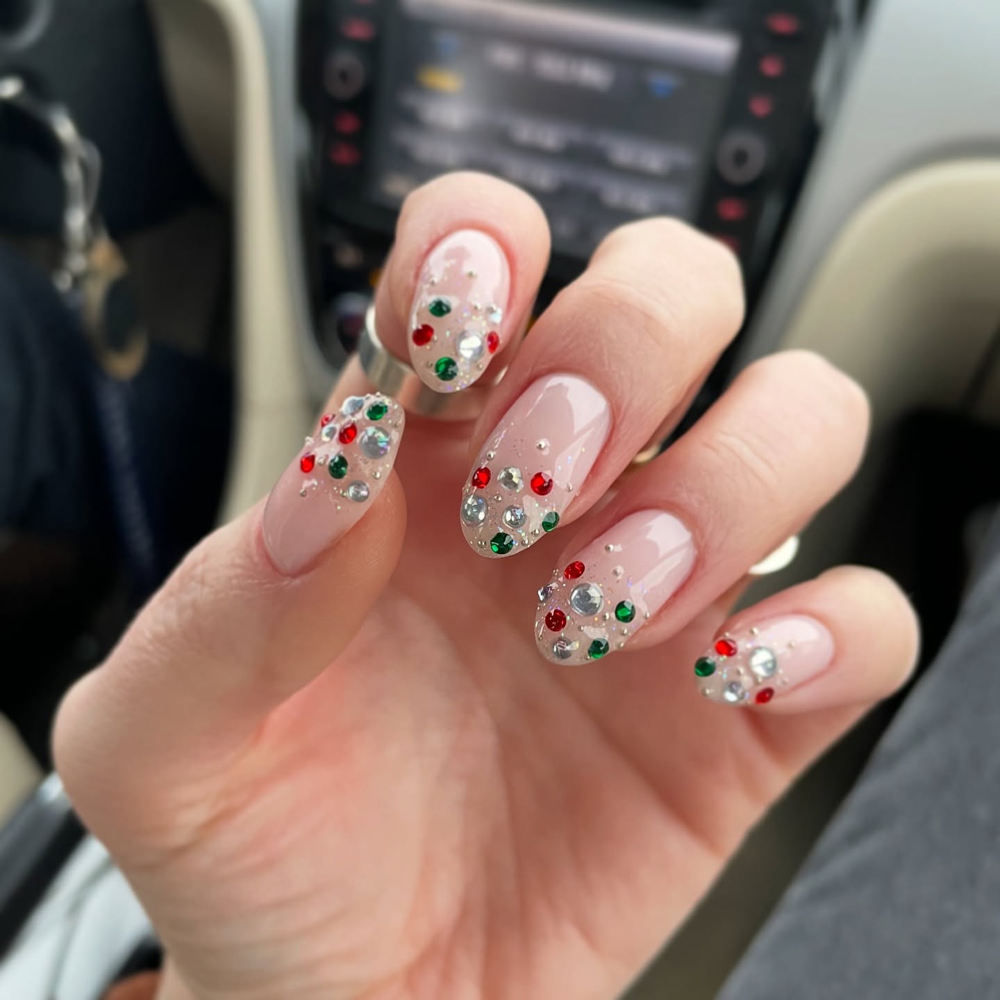 Short square nails with a sheer base featuring red, green and silver rhinestone holiday clusters