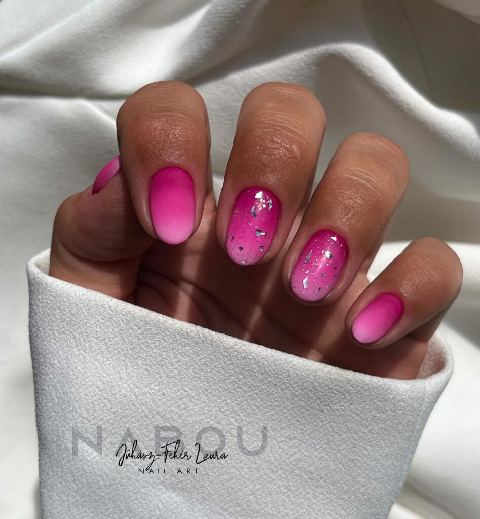 Short round nails with a hot pink matte ombre base and silver foil flake accent nails