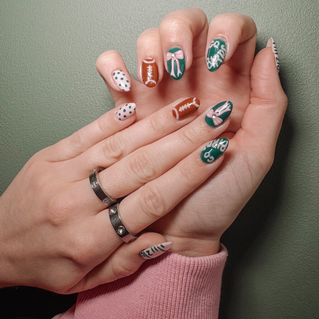 Green and white game day nails with football designs, polka dots, bows, and sporty accents
