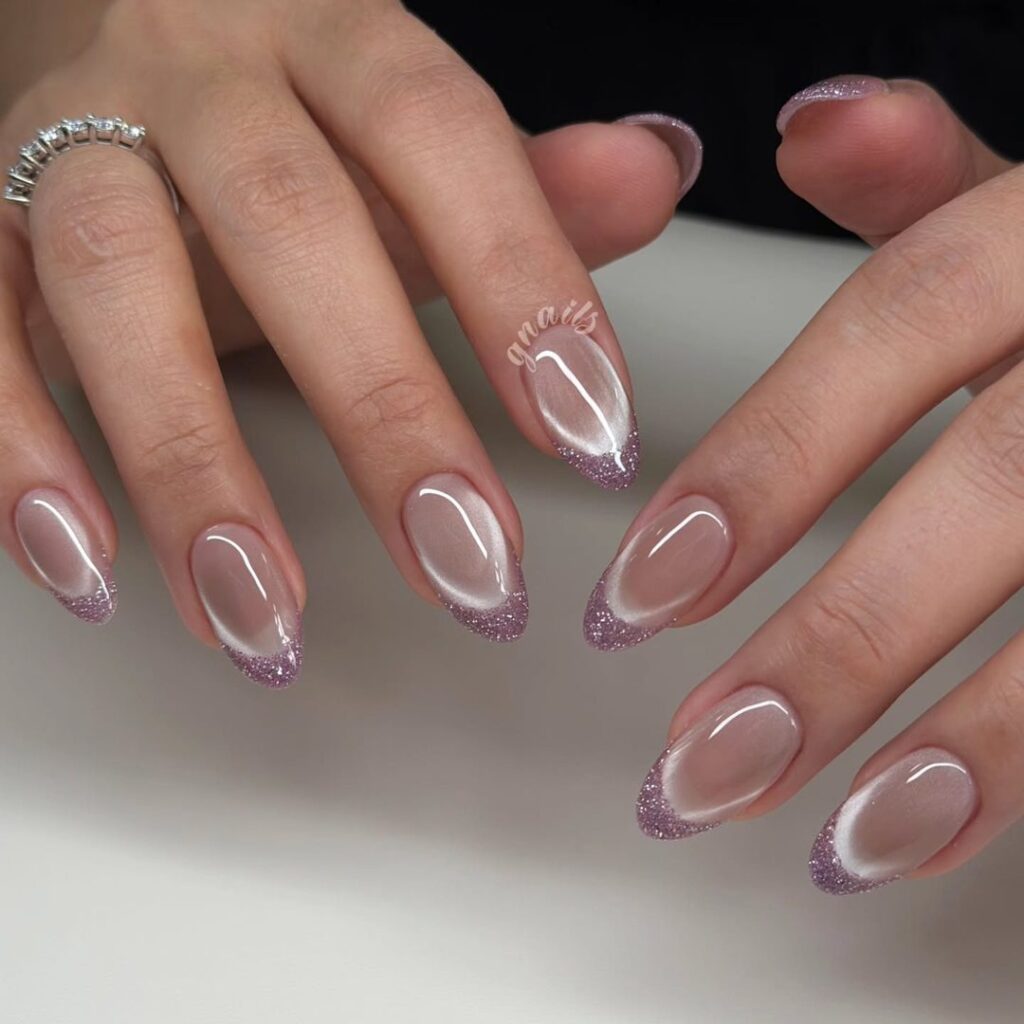 Medium oval nails with lavender purple glitter tips and a white inner tip line on a sheer nude base