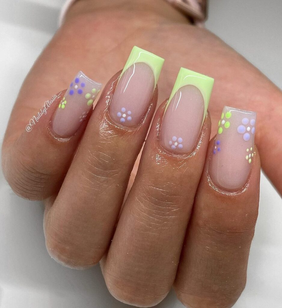 Short square nails with lime green French tips and delicate blue, lavender, and yellow dot flower details on a sheer base