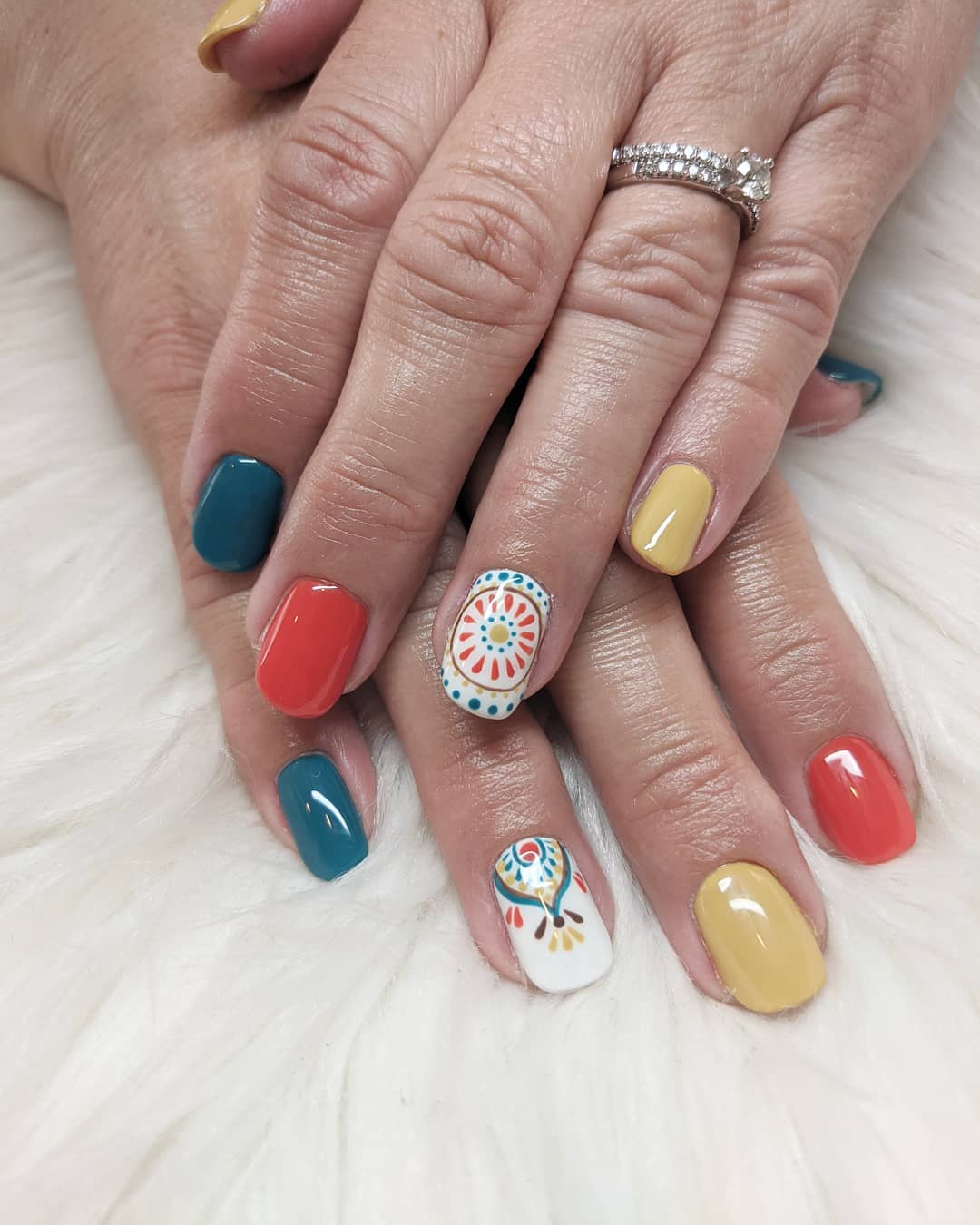 Short square nails in teal, coral red, mustard yellow and white with hand-painted multicolour mandala accent nails