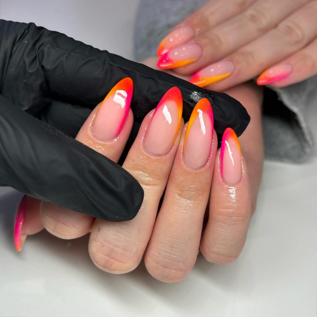 Almond nails with a sheer nude base and neon orange-to-pink ombre French tip