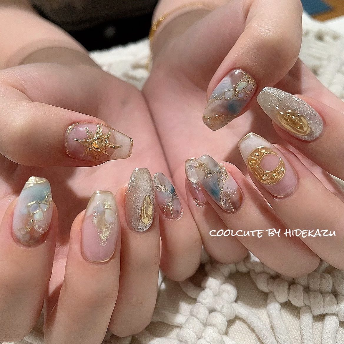 Long coffin nails in shimmering opalescent white and grey with gold sun, crescent moon, planet, and stained glass celestial charms