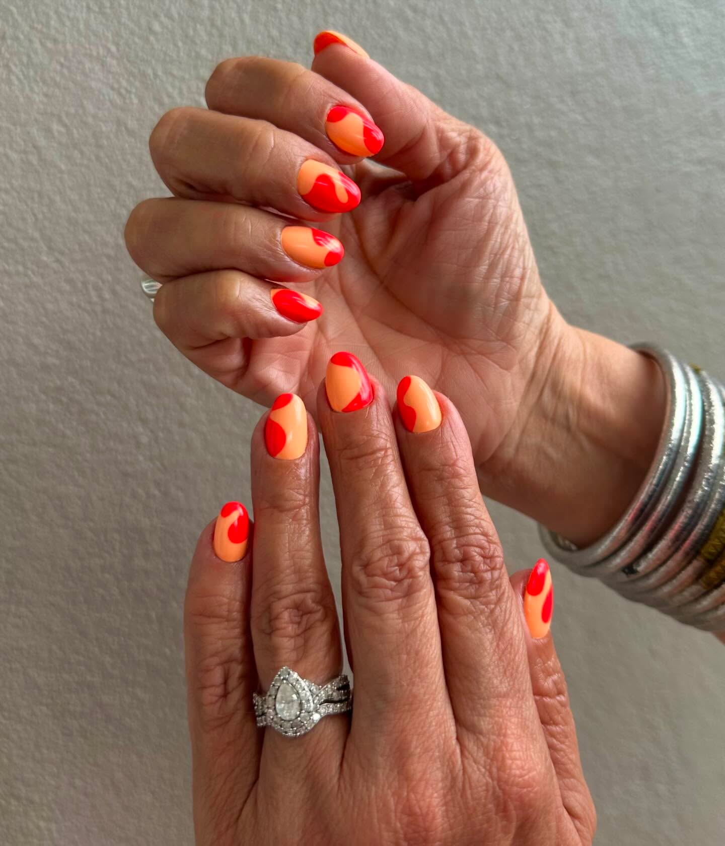 Vivid orange and red nails with negative-space abstract heart shapes