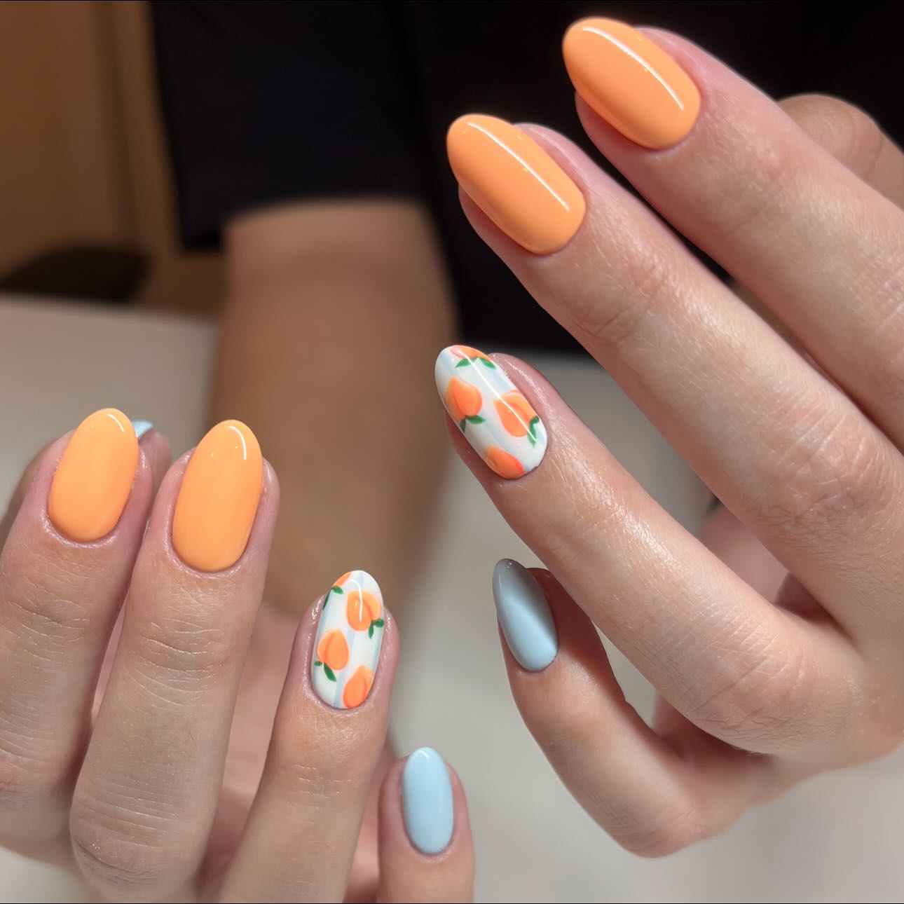 Muted orange nails with a white accent featuring painted peaches and leaves