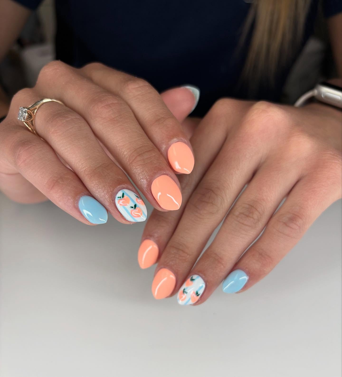 Peach coral and pale blue nails with a painted peach fruit accent